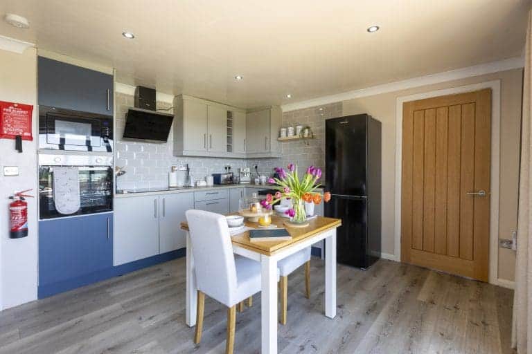 Modern kitchen with white and blue cabinets and a dining table with flowers.