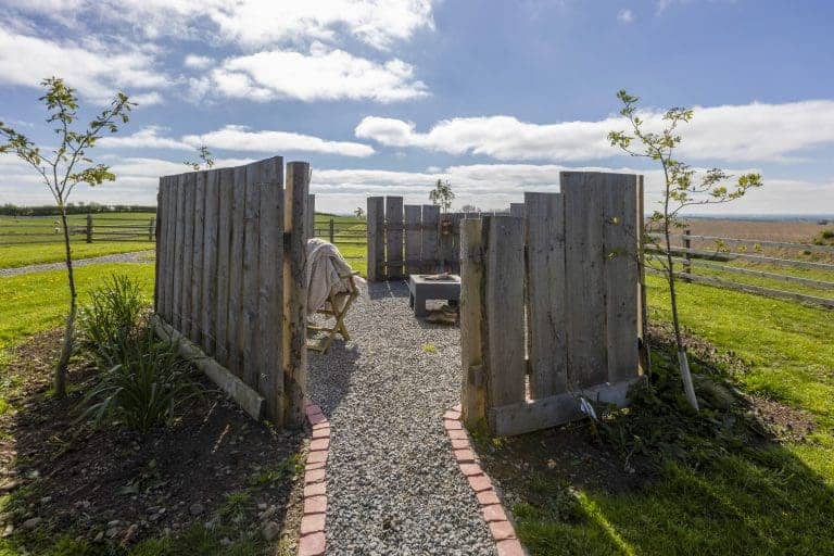Rustic outdoor seating area with wooden fence and scenic countryside view.