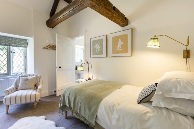 Cozy bedroom at Abbey Cottage with exposed wooden beam and elegant decor.