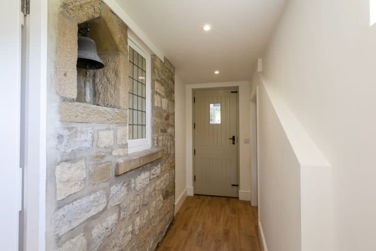 Interior view of Abbey Cottage with stone wall and wooden flooring.