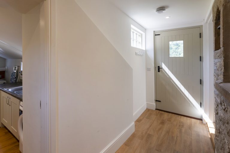 Bright entrance hall with white door and wooden flooring at Abbey Cottage, Rievaulx.