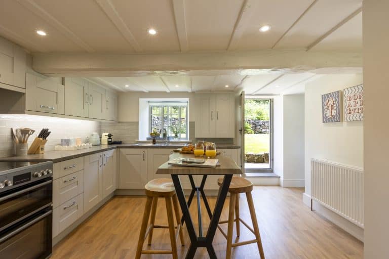 Modern kitchen with white cabinets and wooden island in Yorkshire cottage.