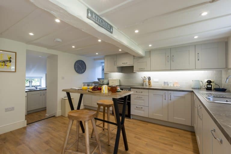 Modern kitchen with white cabinets and wooden flooring at Abbey Cottage, Rievaulx.