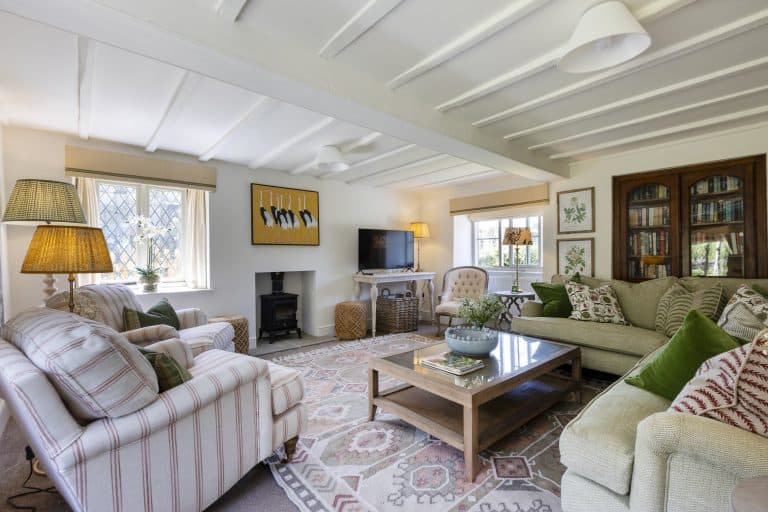 Cozy living room with striped armchair, sofa, and wooden cabinet in Abbey Cottage.