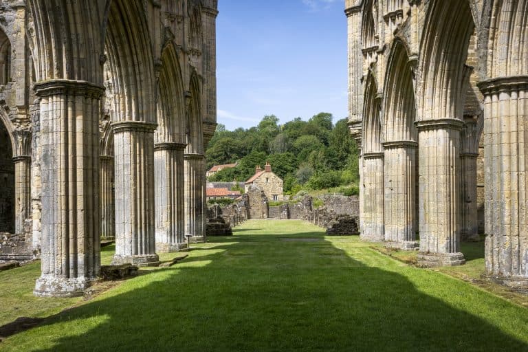 Ancient stone ruins with tall arches and green grass in Yorkshire.