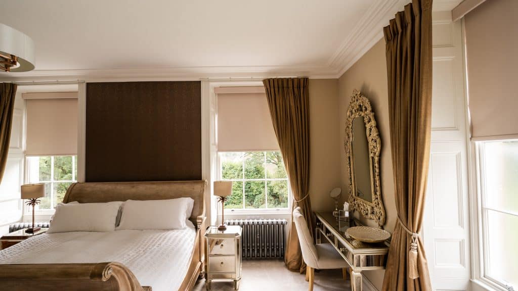 Elegant bedroom with large windows, luxurious curtains, and classic decor for wellness retreats.