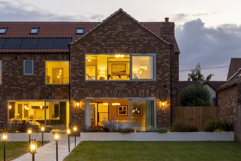 Modern brick house with large illuminated windows at dusk near York.