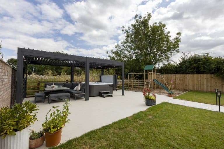 Modern outdoor patio with seating and a children's play area in a garden.