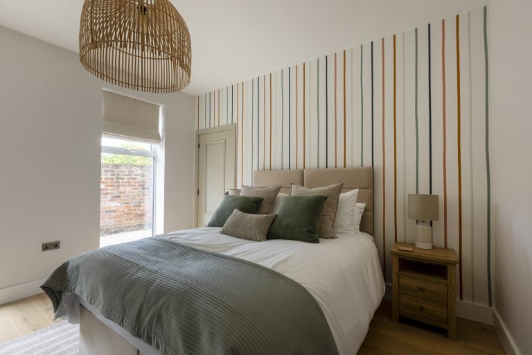 Modern bedroom with striped feature wall and neutral decor in Yorkshire Escapes.