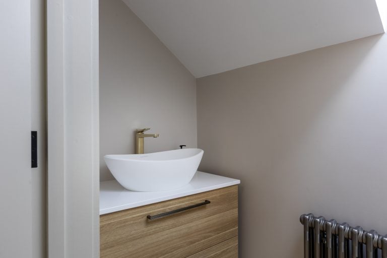 Modern bathroom sink with vessel basin and wooden vanity in a minimalist space.