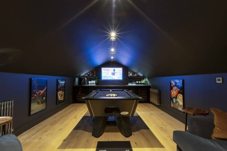 Indoor game room with pool table and colourful artwork on dark blue walls.