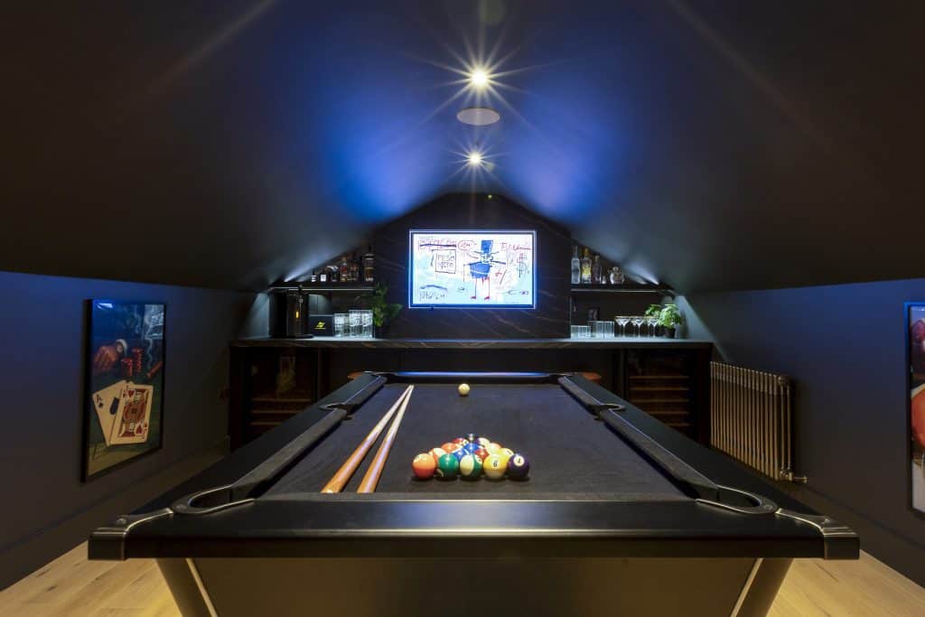 Indoor snooker room with black table and TV screen on dark blue walls.