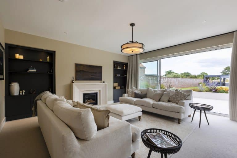 Modern living room with beige sofas and large window overlooking garden.
