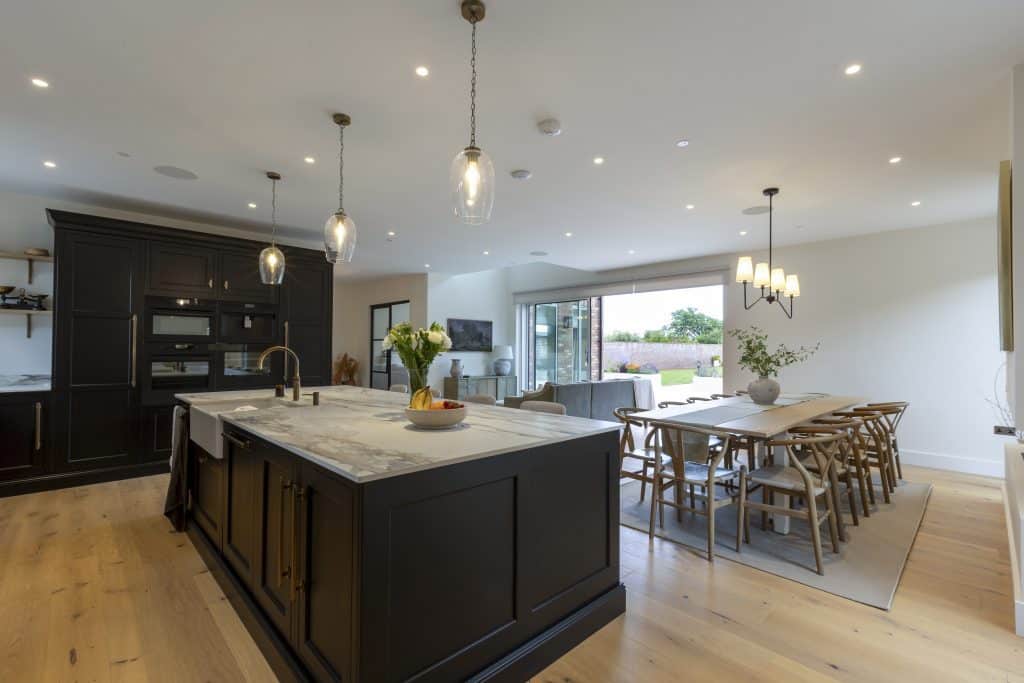 Modern open-plan kitchen and dining area with black cabinetry and wooden flooring.