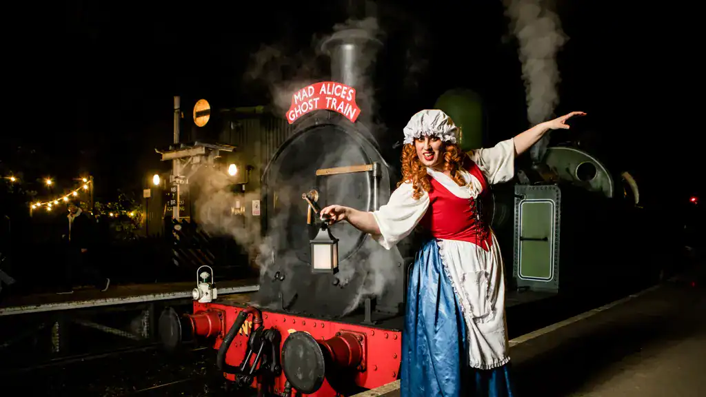Woman in Victorian costume at haunted train station with steam and lights.